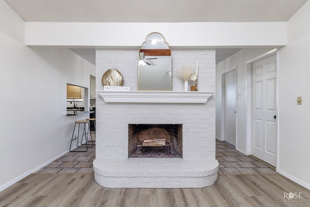 1216 Ricks Ct, San Angelo, TX 76905 - detailed view of a brick fireplace, wood finished floors, baseboards, and ceiling fan