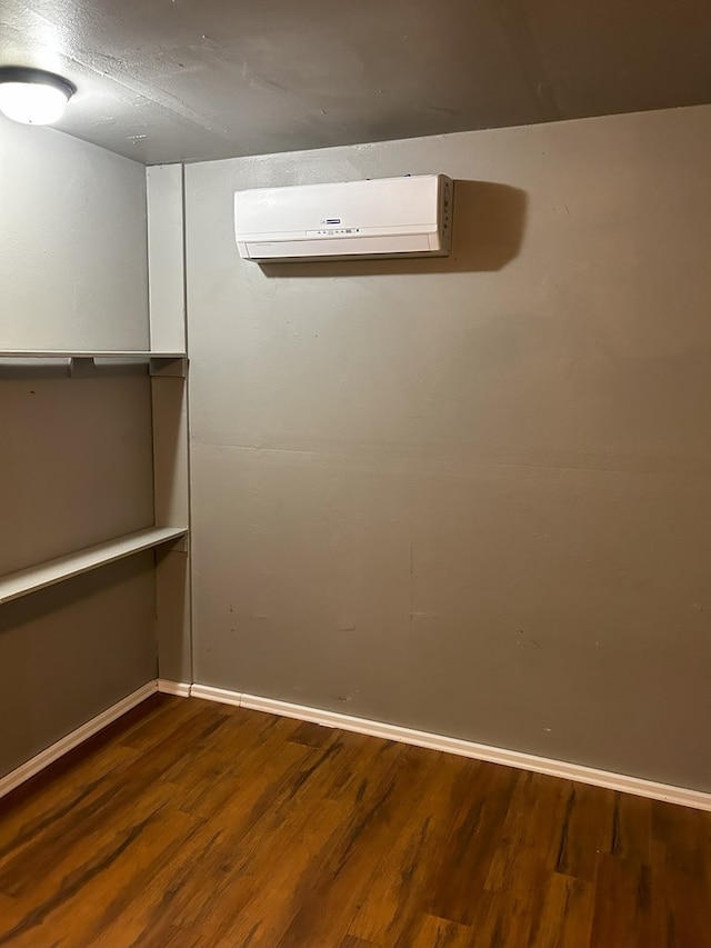 basement with hardwood / wood-style flooring, a wall unit AC, and a textured ceiling