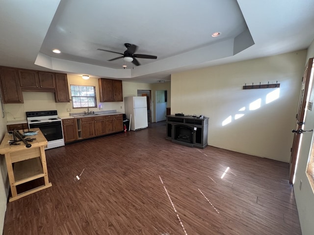 kitchen featuring white refrigerator, range with electric cooktop, a raised ceiling, and dark wood-type flooring