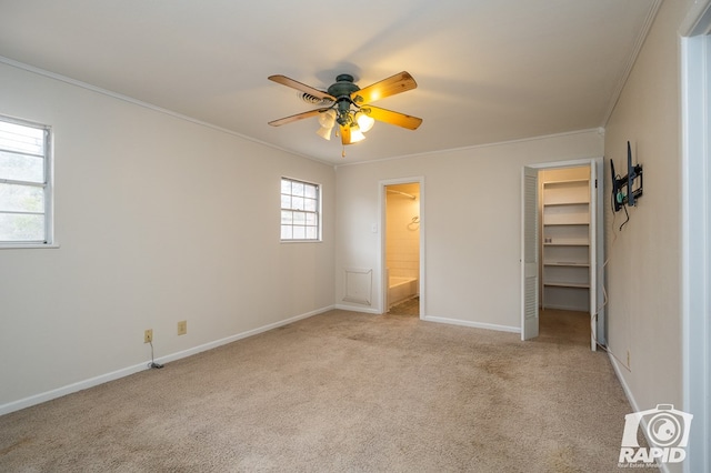 unfurnished bedroom with a walk in closet, ceiling fan, crown molding, light carpet, and a closet