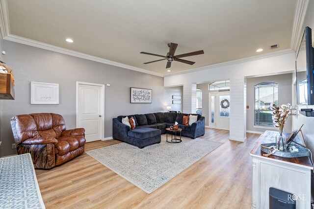 living room featuring ornate columns, crown molding, and light wood-type flooring