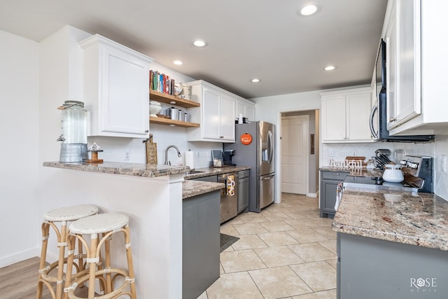 kitchen with a breakfast bar area, stainless steel appliances, and white cabinets