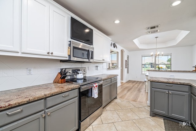 kitchen featuring light tile patterned flooring, appliances with stainless steel finishes, gray cabinetry, white cabinets, and a tray ceiling