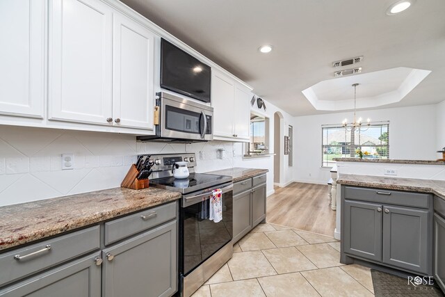 kitchen with gray cabinets, a raised ceiling, appliances with stainless steel finishes, white cabinets, and decorative backsplash