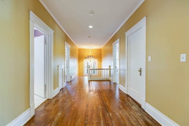 hallway with hardwood / wood-style floors, crown molding, and a chandelier