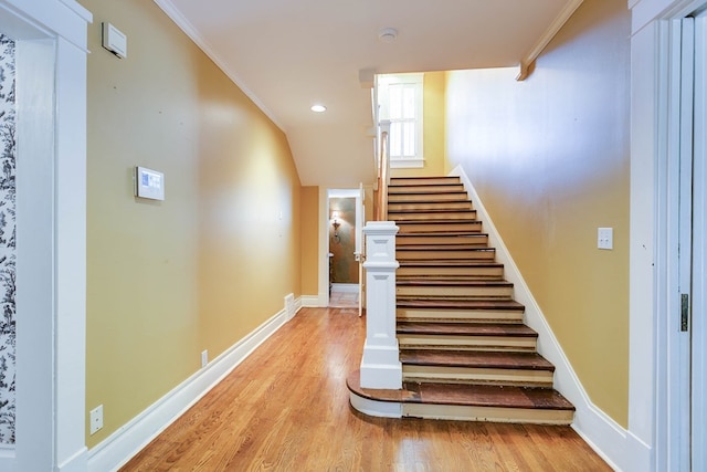 staircase featuring wood-type flooring and crown molding