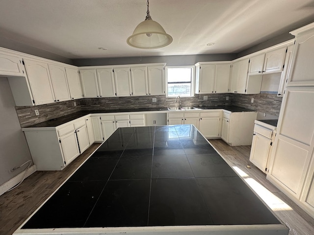 kitchen with pendant lighting, white cabinetry, tile countertops, and sink