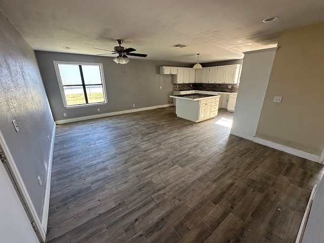 kitchen with white cabinetry, decorative light fixtures, a center island, dark hardwood / wood-style flooring, and backsplash