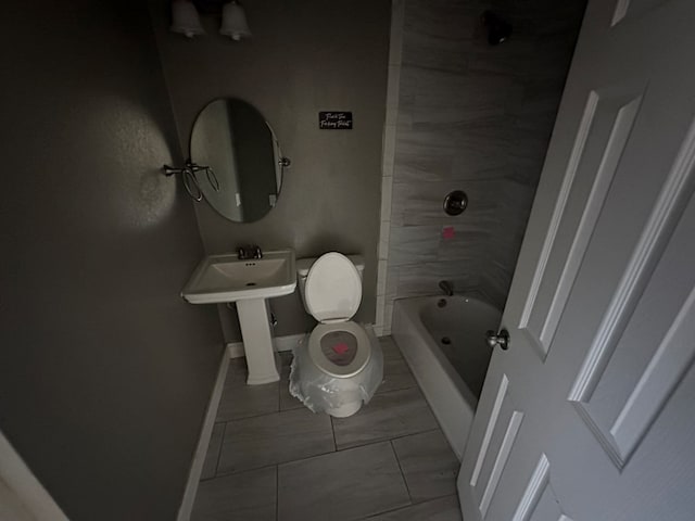 bathroom featuring tiled shower / bath combo, tile patterned floors, and toilet