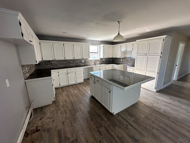 kitchen with sink, tile countertops, a center island, hanging light fixtures, and white cabinets