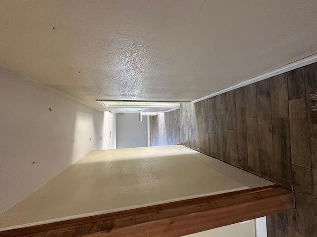 spare room with a textured ceiling and wooden walls