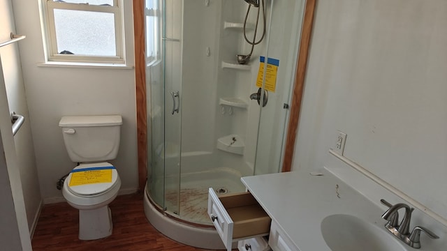 full bath with wood finished floors, baseboards, a sink, a shower stall, and toilet