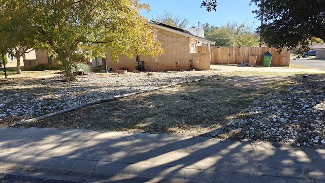 view of side of property featuring brick siding and fence