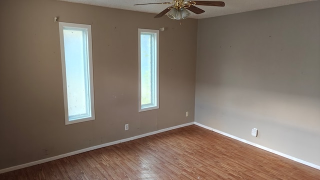 spare room with ceiling fan, baseboards, a textured ceiling, and wood finished floors