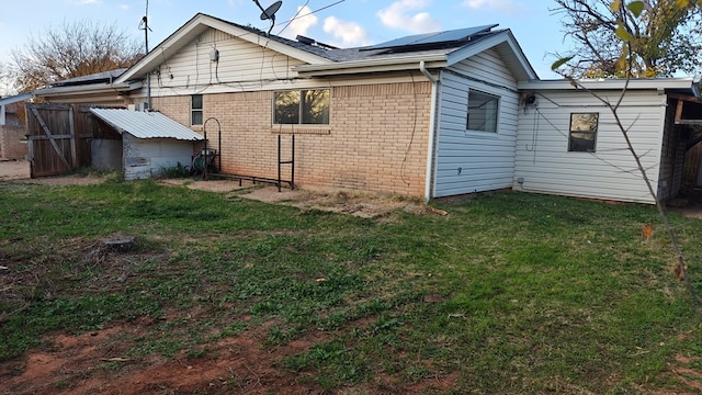 back of house with solar panels, a yard, and brick siding