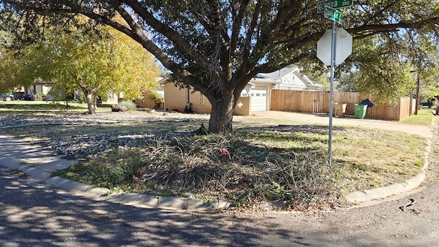 view of yard featuring an attached garage, concrete driveway, and fence