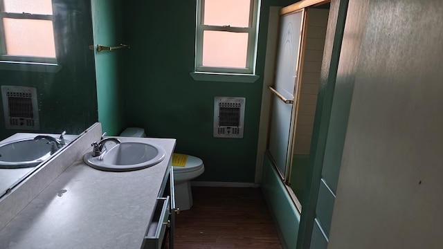 full bath featuring vanity, heating unit, wood finished floors, baseboards, and toilet