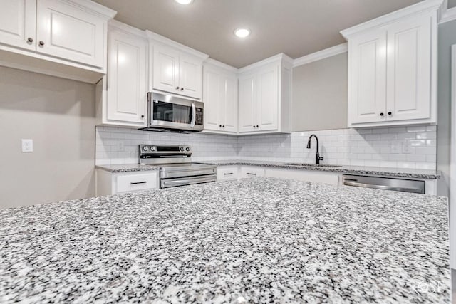 kitchen featuring ornamental molding, appliances with stainless steel finishes, sink, and white cabinets