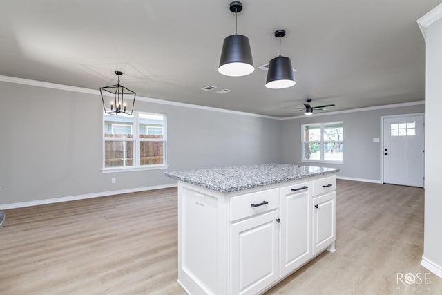 kitchen with white cabinetry, decorative light fixtures, a center island, and light wood-type flooring