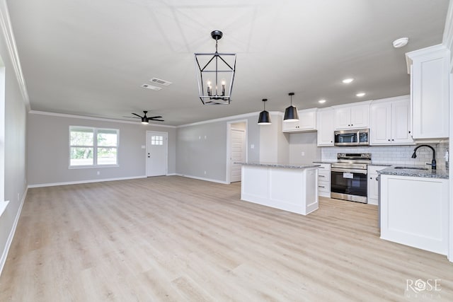 kitchen with pendant lighting, sink, appliances with stainless steel finishes, a center island, and white cabinets