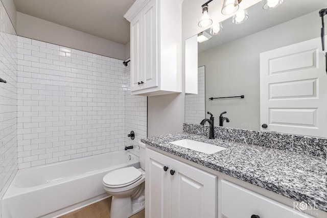 full bathroom with hardwood / wood-style flooring, tiled shower / bath, vanity, and toilet