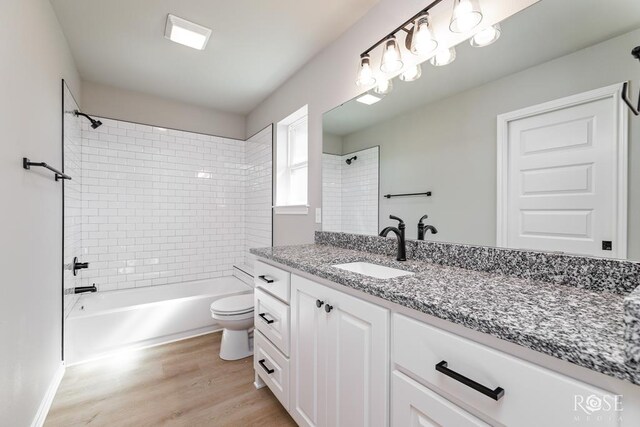 full bathroom with vanity, hardwood / wood-style floors, tiled shower / bath combo, and toilet