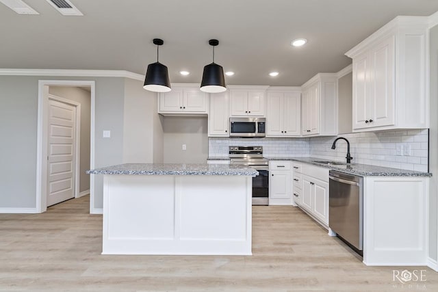 kitchen featuring sink, white cabinetry, stainless steel appliances, a center island, and light stone counters