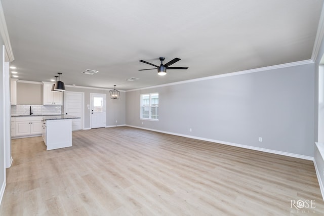 unfurnished living room featuring crown molding, sink, ceiling fan with notable chandelier, and light hardwood / wood-style flooring