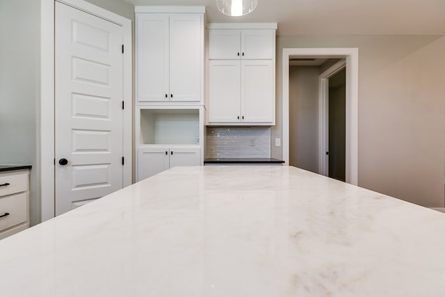 kitchen with tasteful backsplash, white cabinetry, and light stone counters