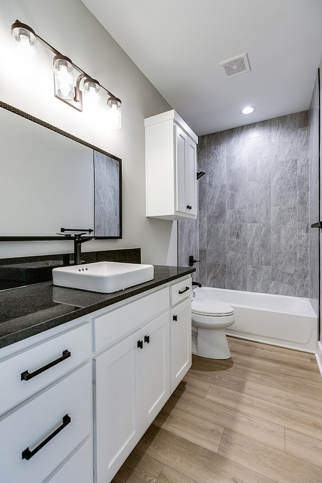 full bathroom featuring tiled shower / bath, vanity, and toilet