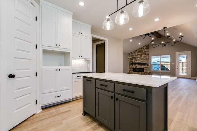 kitchen featuring white cabinetry, backsplash, decorative light fixtures, and lofted ceiling