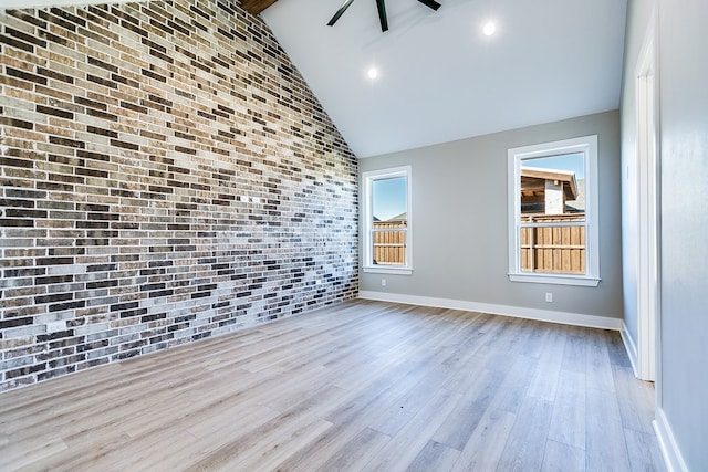 unfurnished living room featuring brick wall, high vaulted ceiling, and light hardwood / wood-style flooring