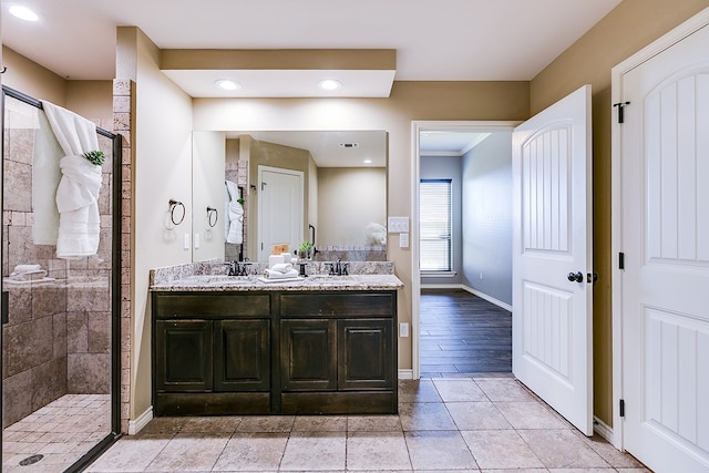 bathroom with vanity, crown molding, and a tile shower