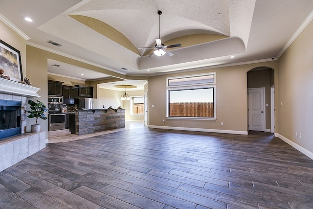 unfurnished living room with crown molding, ceiling fan, a tray ceiling, and a tile fireplace