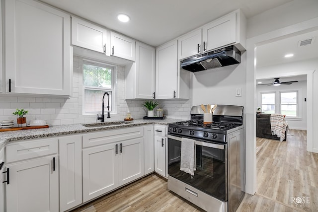 935 E 40th St, San Angelo, TX 76903 - kitchen with stainless steel gas range, under cabinet range hood, white cabinets, light wood-style floors, and recessed lighting