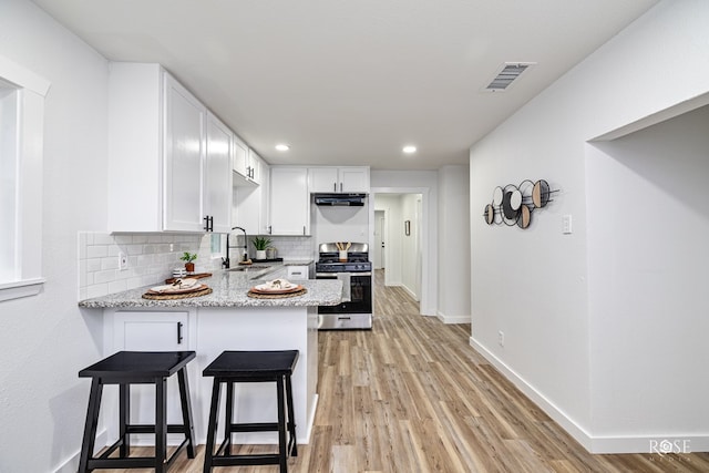 935 E 40th St, San Angelo, TX 76903 - kitchen featuring stainless steel range with gas cooktop, backsplash, white cabinets, a peninsula, and light stone countertops