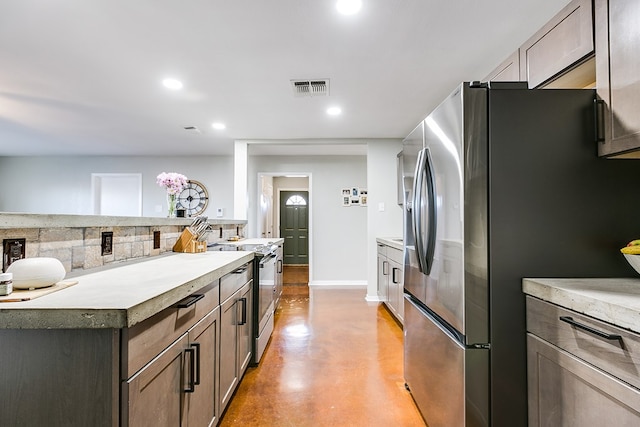 718 E 45th St, San Angelo, TX 76903 - kitchen featuring freestanding refrigerator, range, finished concrete flooring, tasteful backsplash, and recessed lighting