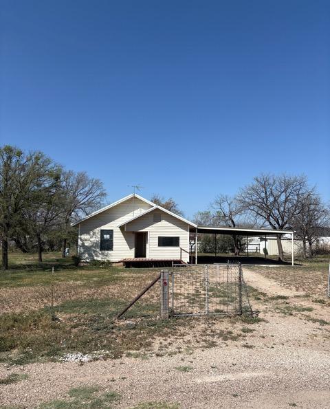 view of side of home with fence, dirt driveway, and an attached carport