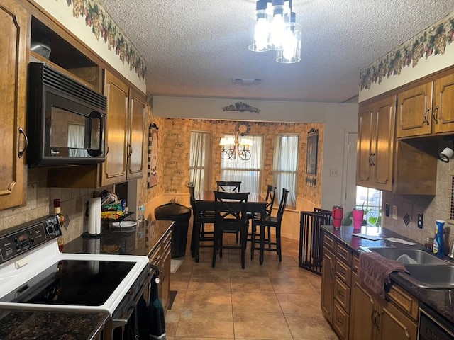 kitchen with light tile patterned flooring, decorative backsplash, a notable chandelier, black appliances, and a textured ceiling