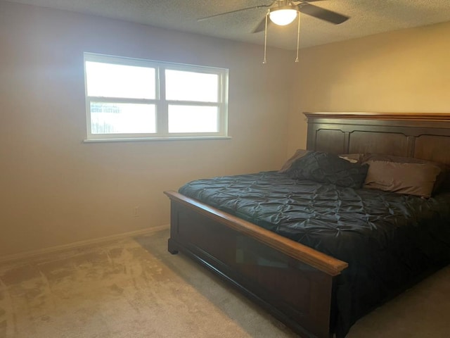 bedroom with light colored carpet, a textured ceiling, and ceiling fan