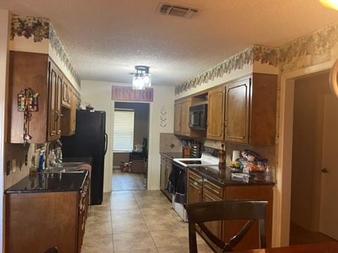 kitchen featuring sink, light tile patterned floors, a textured ceiling, and black appliances