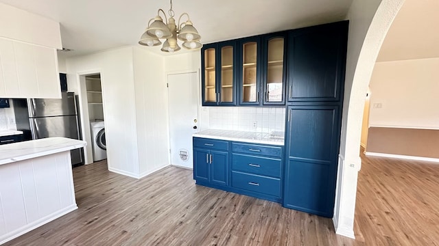 kitchen with blue cabinetry, washer / dryer, light hardwood / wood-style floors, and stainless steel refrigerator