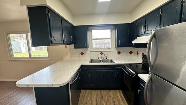 kitchen with sink, tasteful backsplash, black appliances, kitchen peninsula, and light wood-type flooring