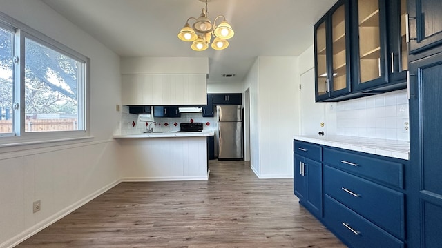 kitchen featuring sink, hardwood / wood-style flooring, stainless steel fridge, an inviting chandelier, and blue cabinets