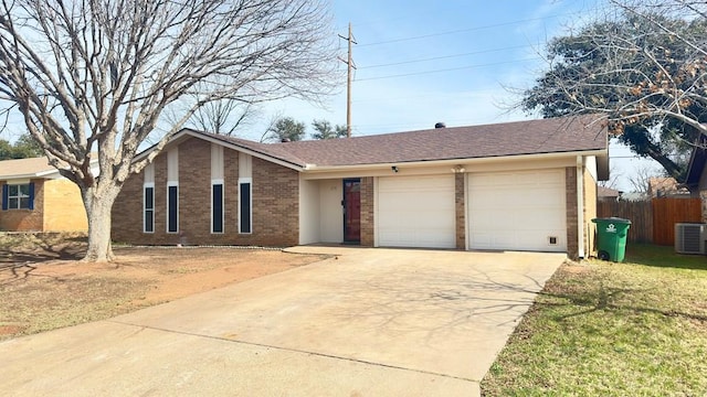 single story home featuring a garage, a front lawn, and central air condition unit