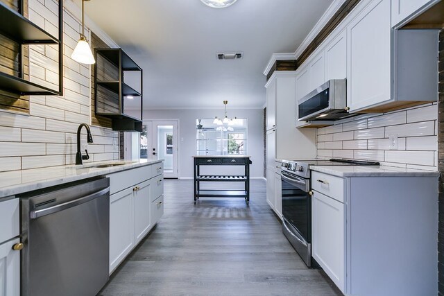 kitchen featuring pendant lighting, sink, appliances with stainless steel finishes, white cabinetry, and ornamental molding