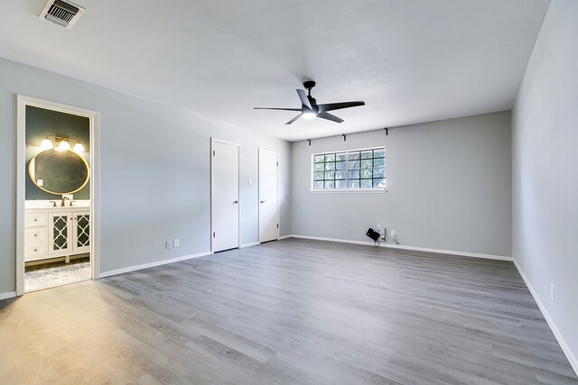 unfurnished bedroom featuring ensuite bathroom, wood-type flooring, and ceiling fan