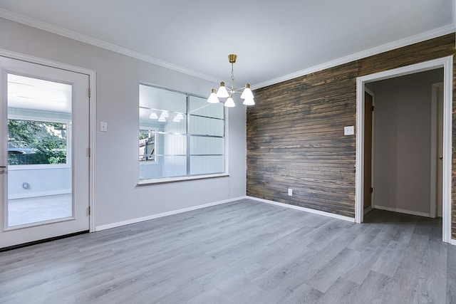 unfurnished dining area featuring crown molding, a chandelier, hardwood / wood-style floors, and a wealth of natural light