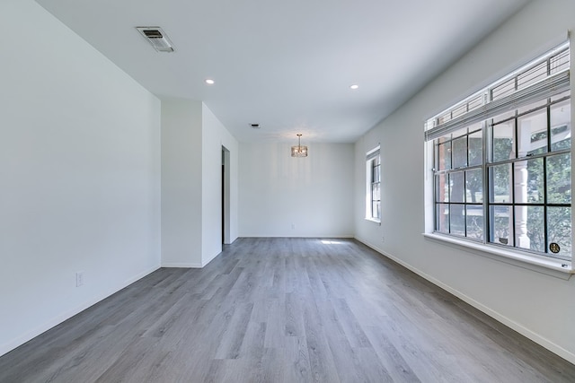 unfurnished room with a notable chandelier and light hardwood / wood-style floors