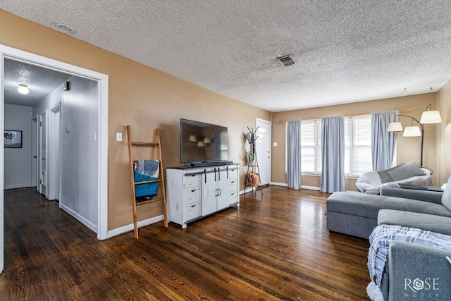 living room with visible vents, a textured ceiling, baseboards, and wood finished floors